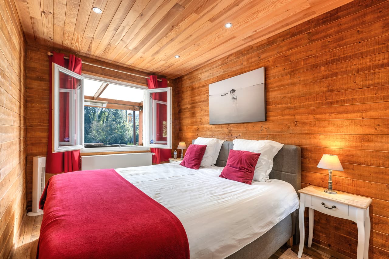 Wood bedroom with a red throw and open windows