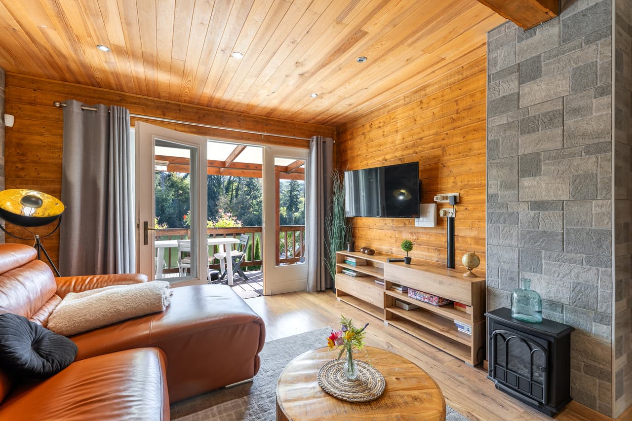 Television corner in the living room, wood walls and ceiling, leather sofa and glass door to the terrace