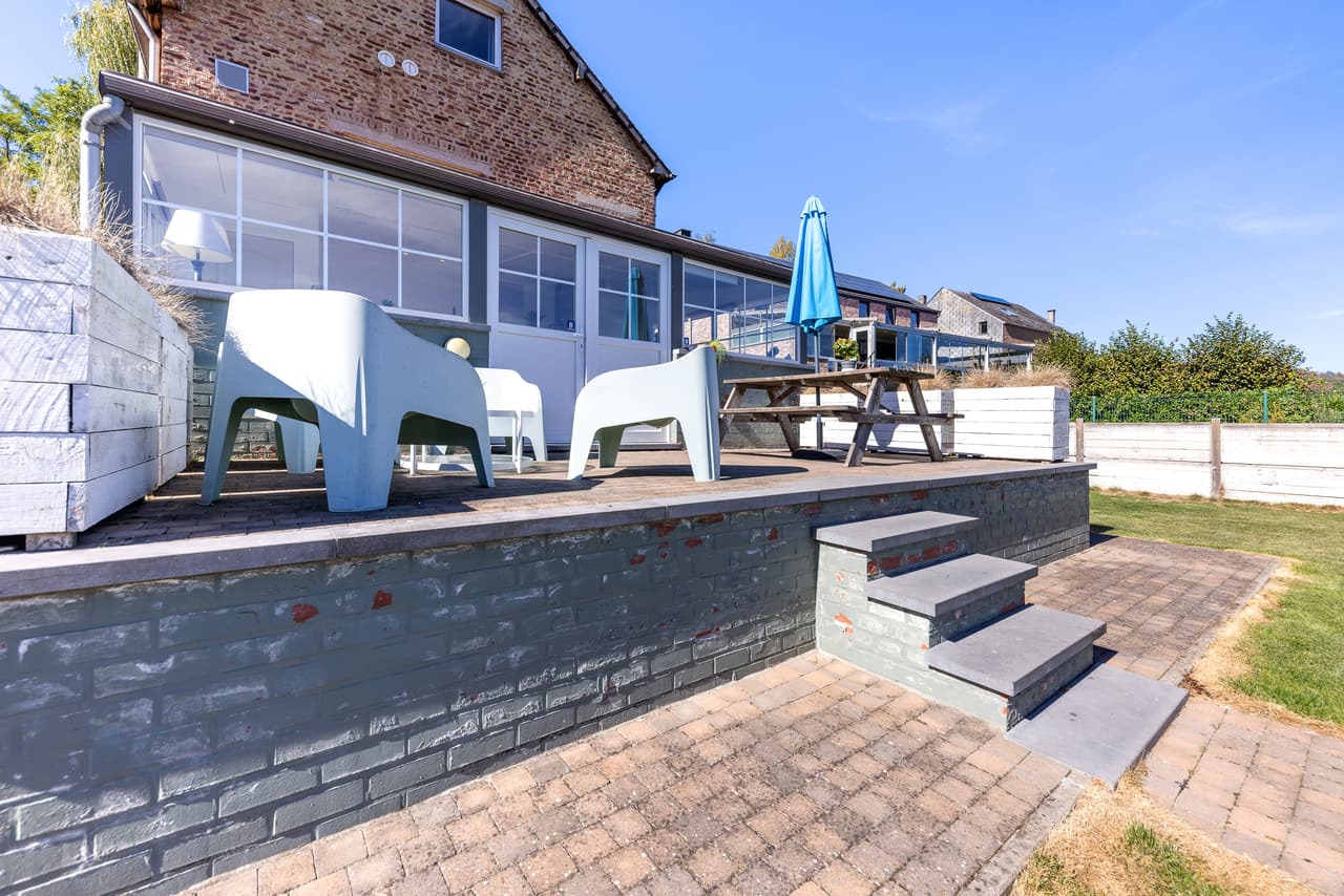 Raised terrace with chairs and a table, along the veranda