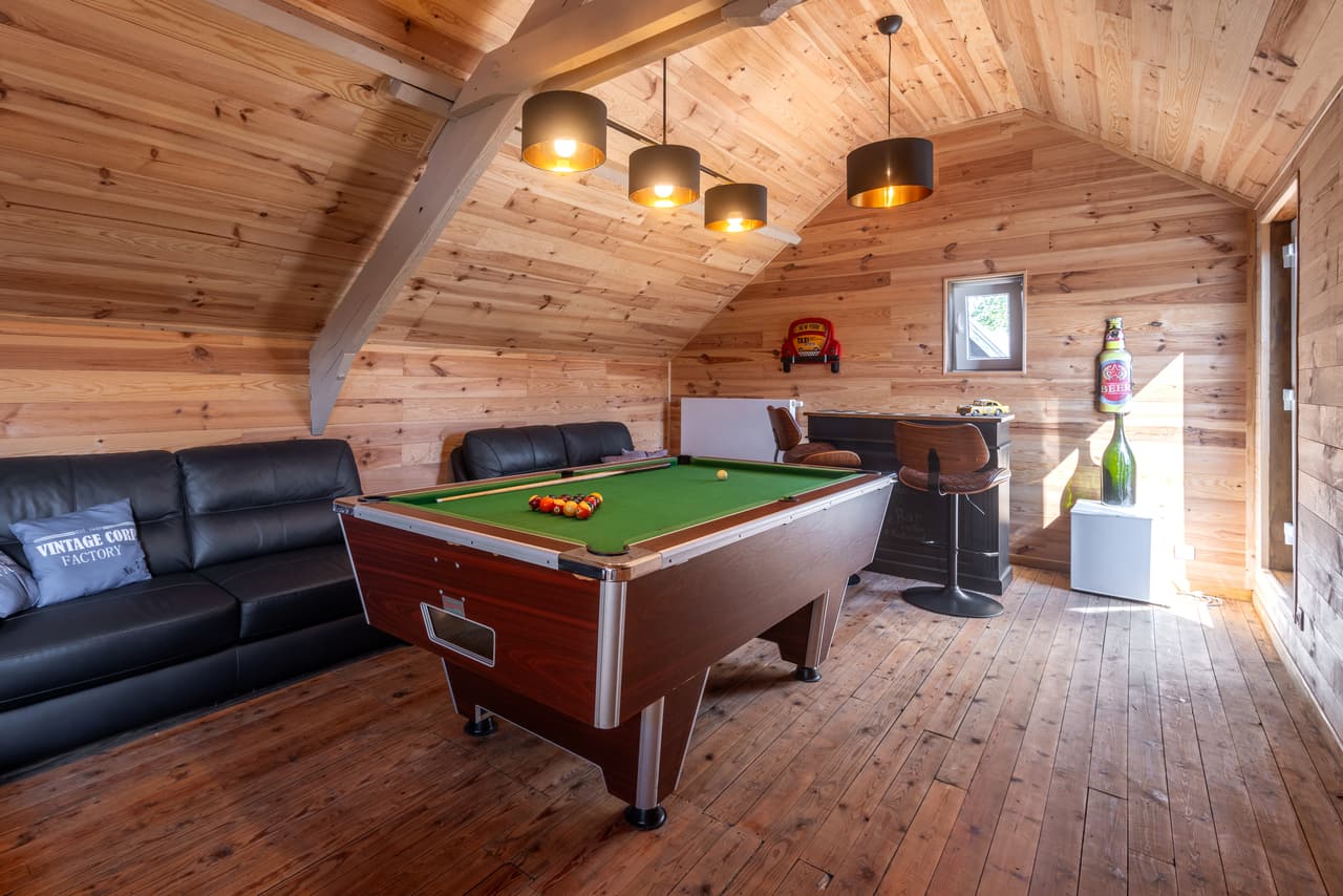 American pool table under the eaves, with a leather sofa