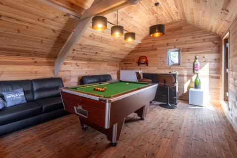 American pool table under the eaves, with a leather sofa