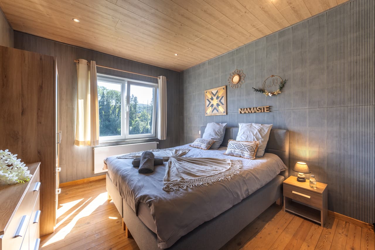Grey bedroom with a large bed and a window onto the trees