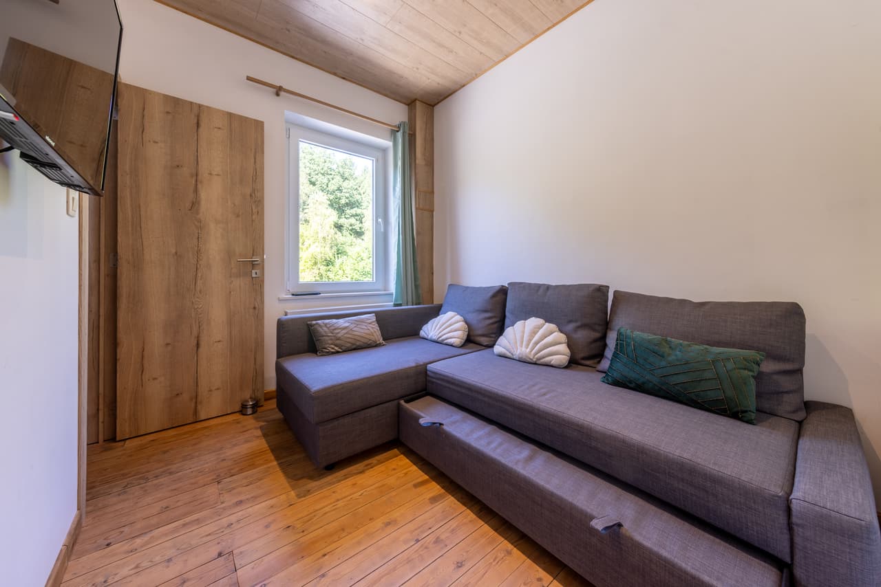 TV corner with a grey sofa bed and the trundle bed pulled out