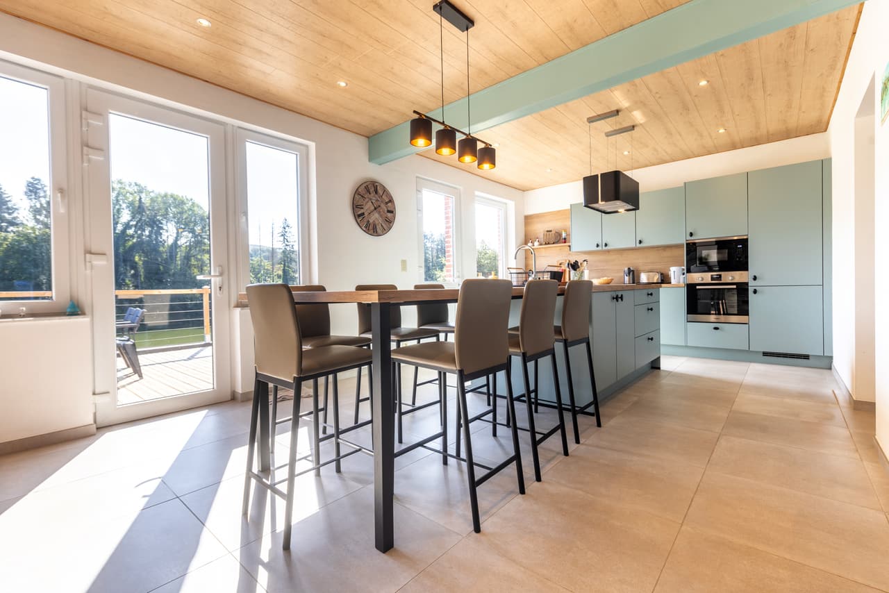 Kitchen with a large table, stools and glazed doors to the terrace