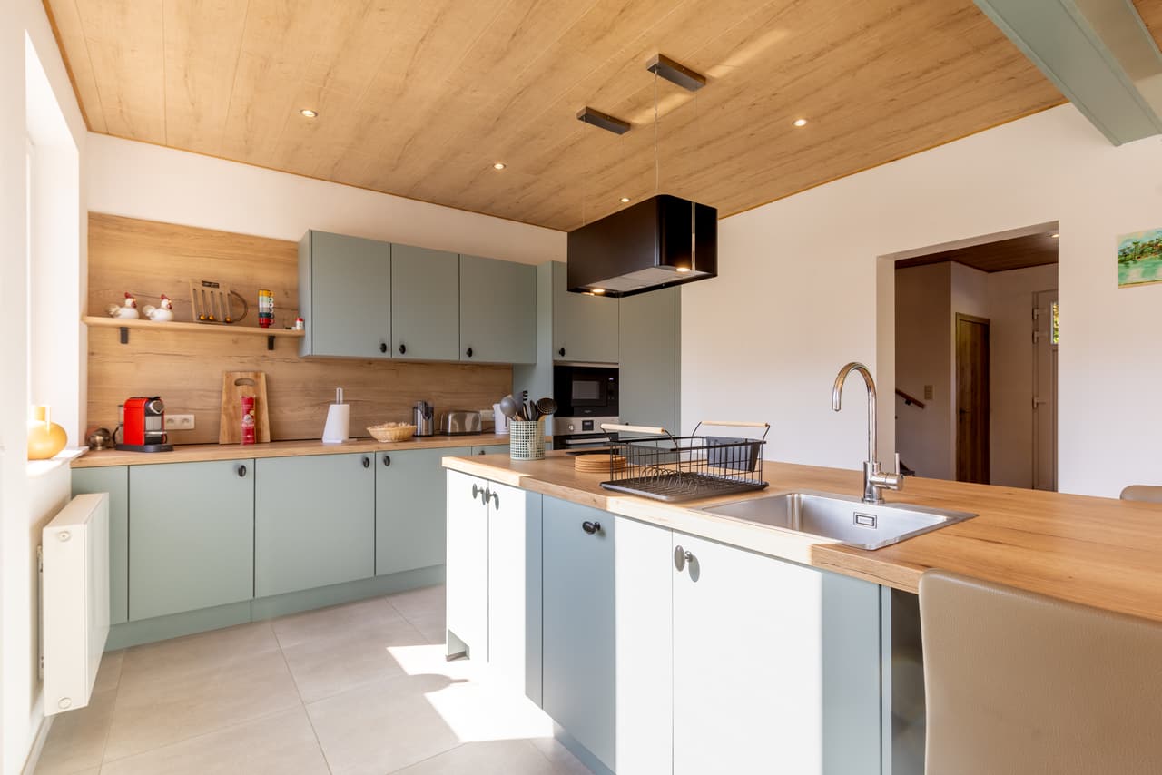 Kitchen island with sink, hob and sage-green cabinets