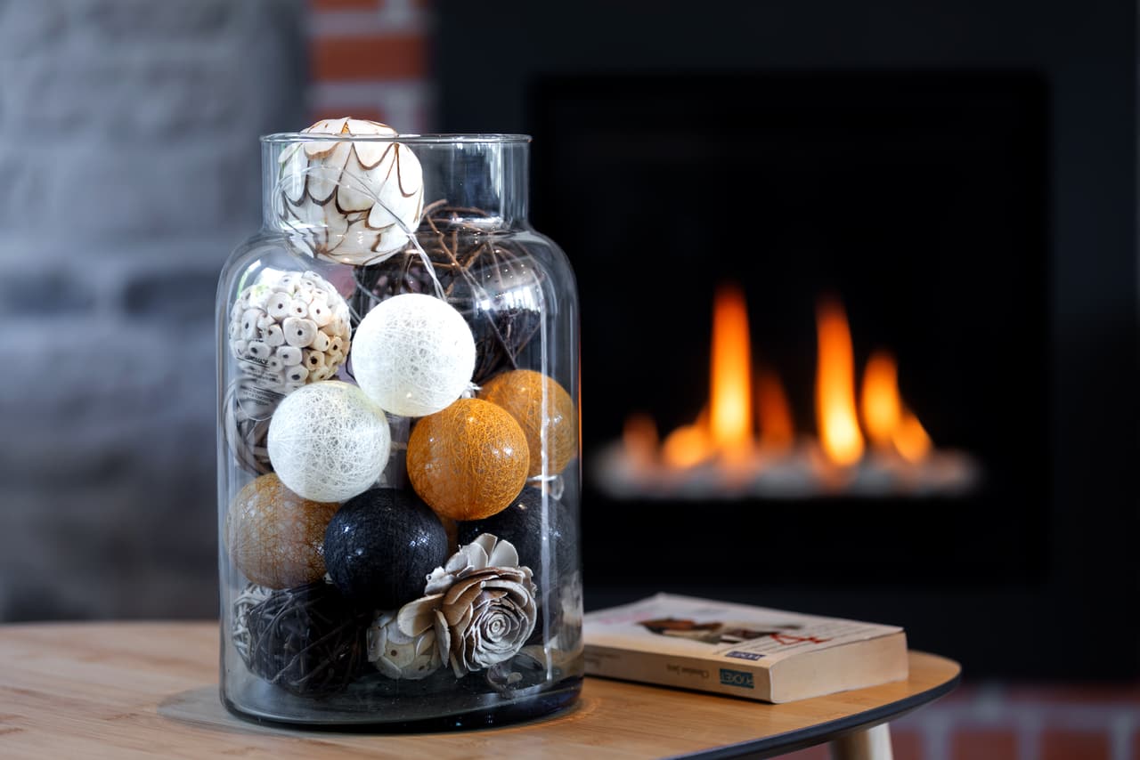 Decorative glass jar on a table, in front of the lit fire