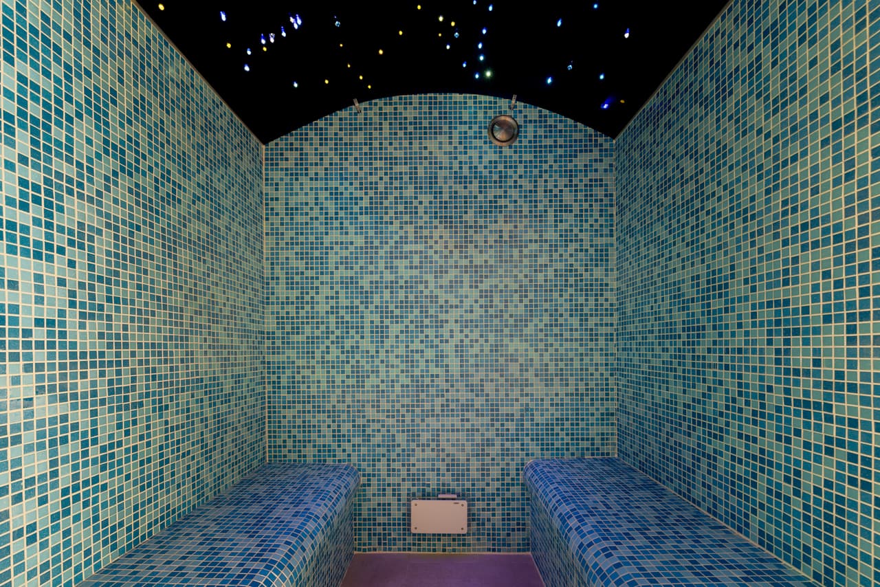 Hammam lined in blue-green mosaic, with a starry ceiling