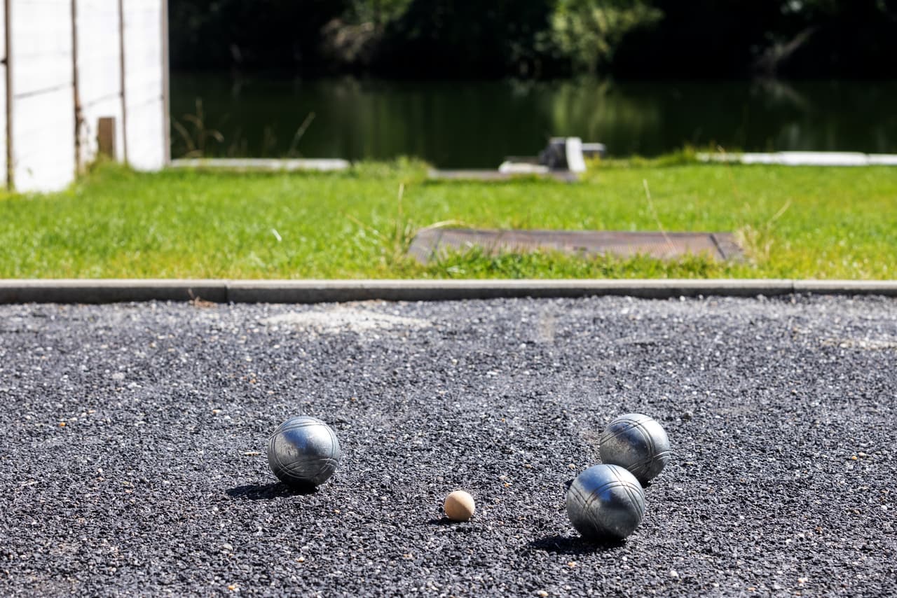 Pétanque bowls in the foreground, the Meuse behind the court